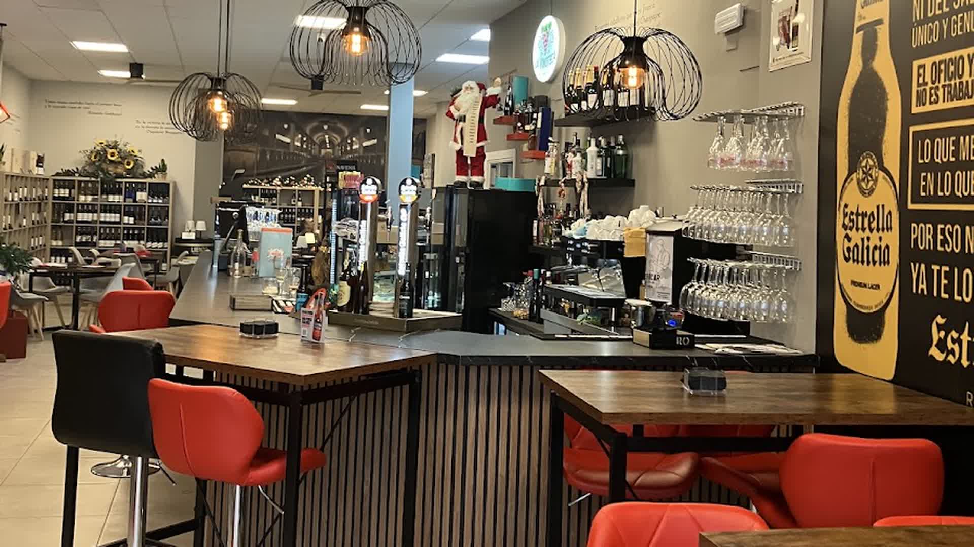 Interior de La Vinoteca de Tomelloso: la barra con los grifos de cerveza, las copas colgadas y las estanterías de vino al fondo